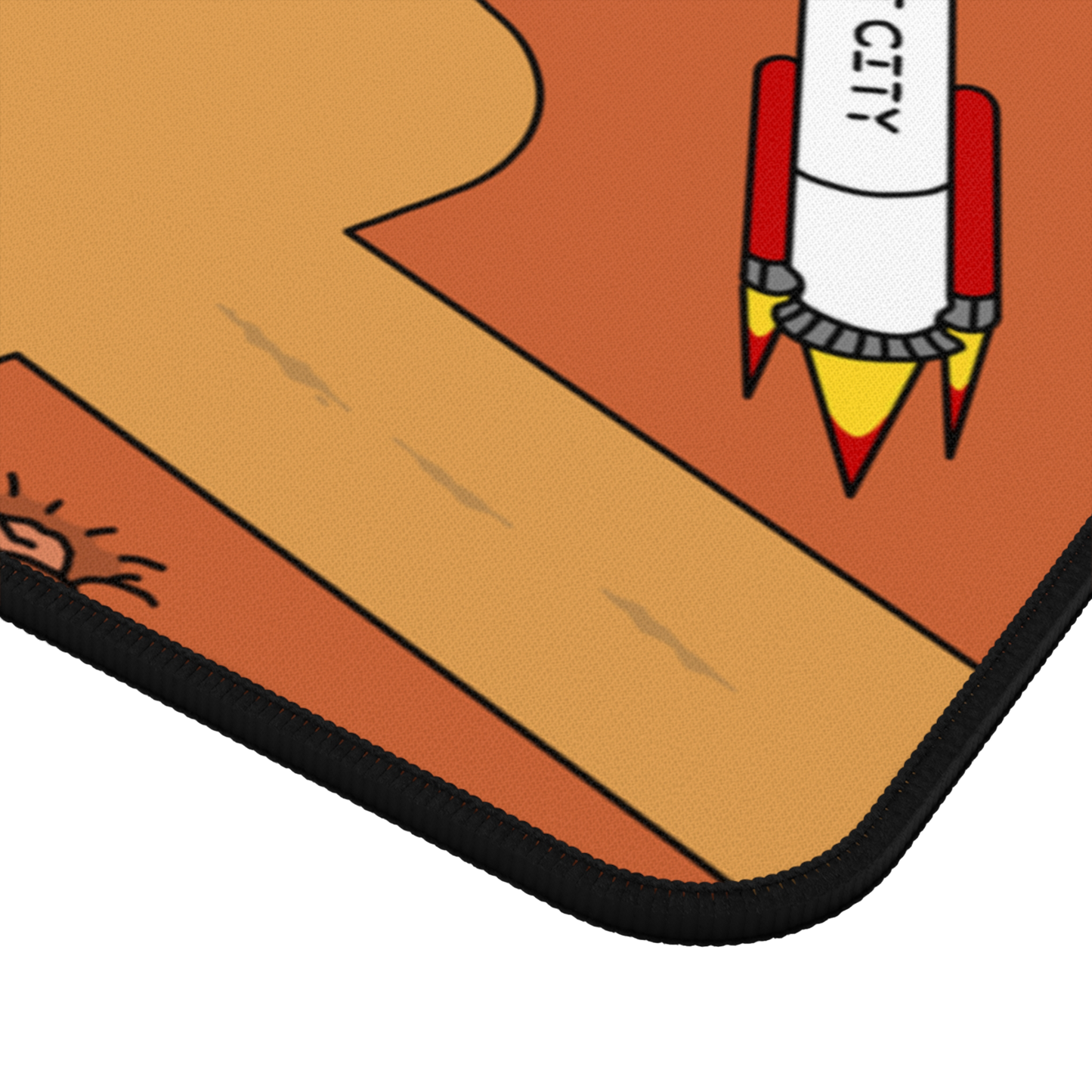 A close-up of a corner of the Matcity Mars Mouse Mat Large, showing its stitched edge and part of a rocket from the playful design.