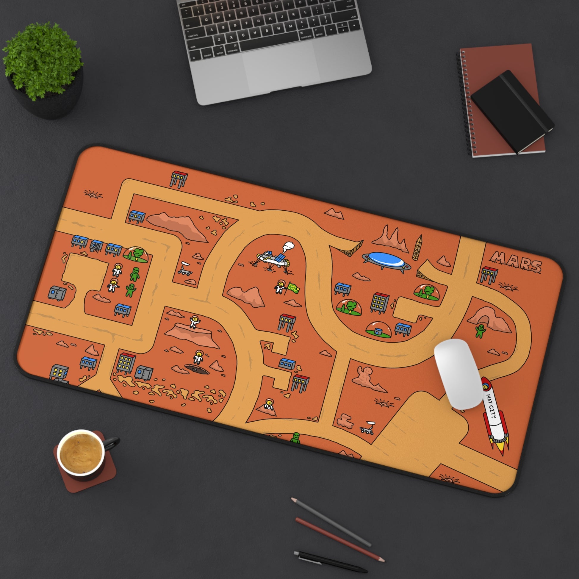 A Matcity Mars Mouse Mat Large placed on a black desk alongside a cup of coffee, pencils, and a laptop, with its colorful Martian landscape standing out.