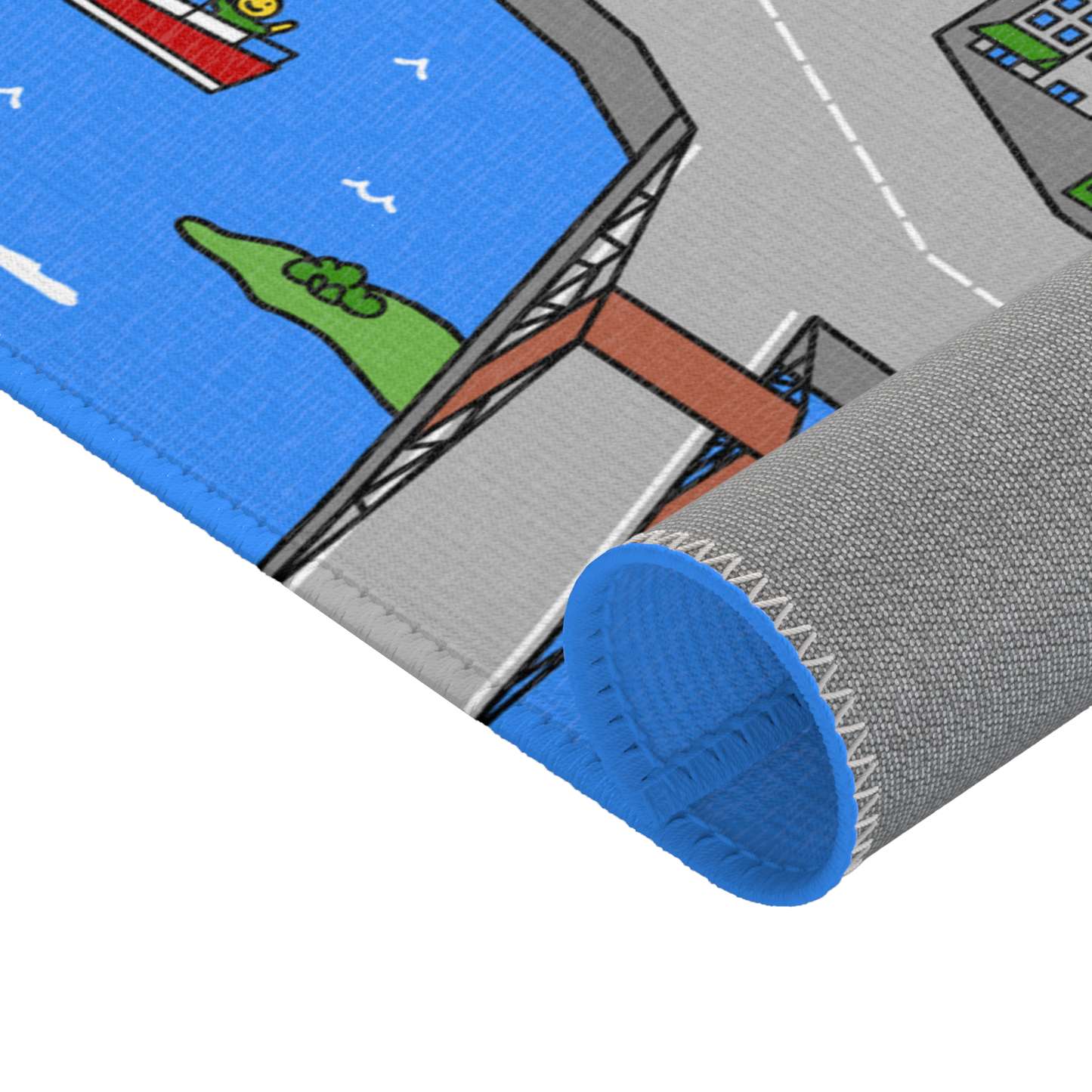 The Matcity New York Mat rolled up, with stitched blue edging visible. The playful design features bridges and boats along a river flowing through the city.