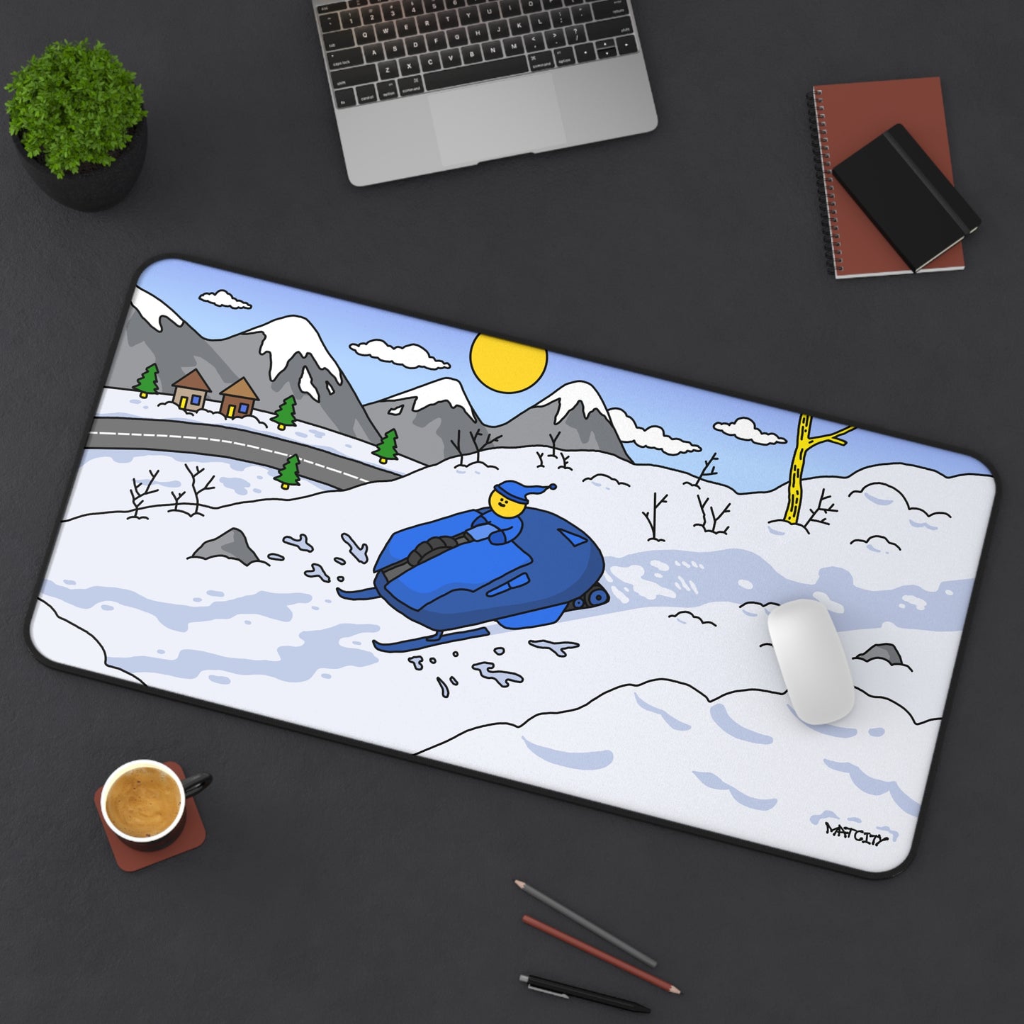 Desk setup with the Snow Rally Mousepad Large, a sled design with snowy mountains and sunny sky, placed under a laptop and mouse.