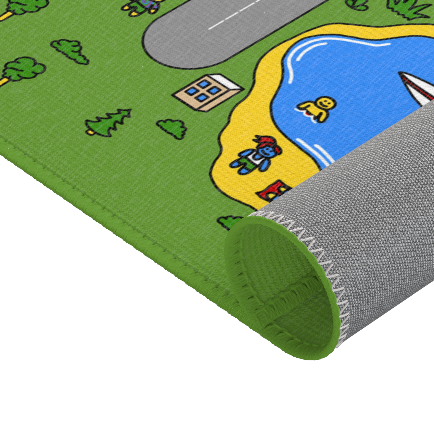A detailed close-up of the Matcity play mat, showing the corner being slightly rolled up to reveal the backside with reinforced stitching. The design includes a section of a road curving near a small pond, with colorful characters on the beach. One character is sunbathing while another is near the water. The stitching around the edge is clearly visible, and the bright green border adds a pop of color to the scene.