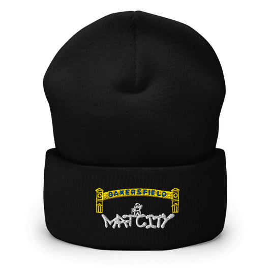 Black knit beanie with folded cuff. Centered embroidery shows a yellow Bakersfield arch over a tiny worker and bold white “Matcity” graffiti lettering.