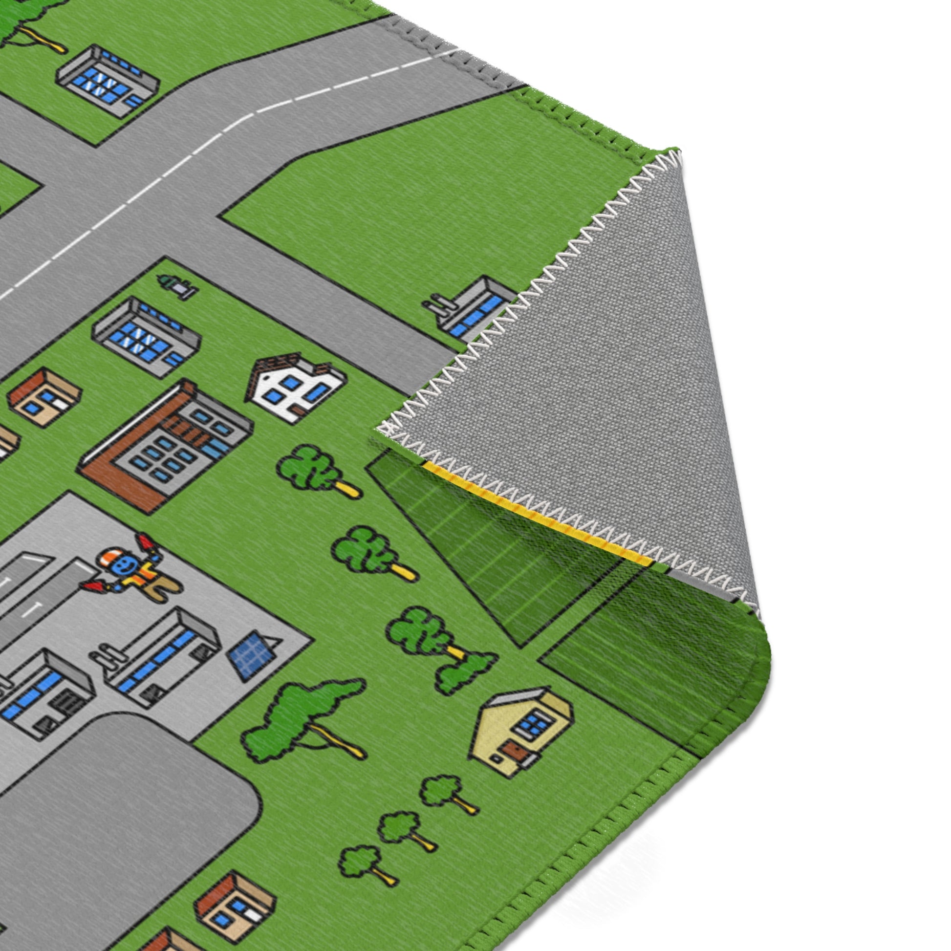 Zoom on a folded corner showing white zig‑zag stitching, grey anti‑slip back trees and houses.