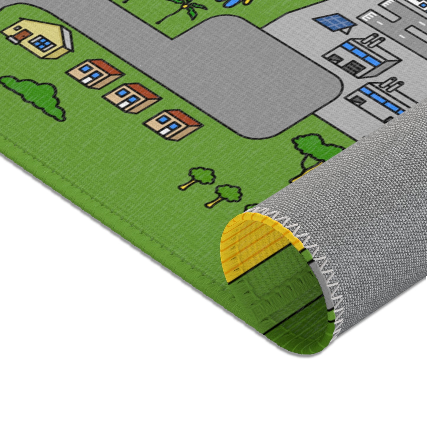 Mat rolled into a tube exposing cushioned yellow underside; visible on top are green fields, grey road and tiny factory graphics.