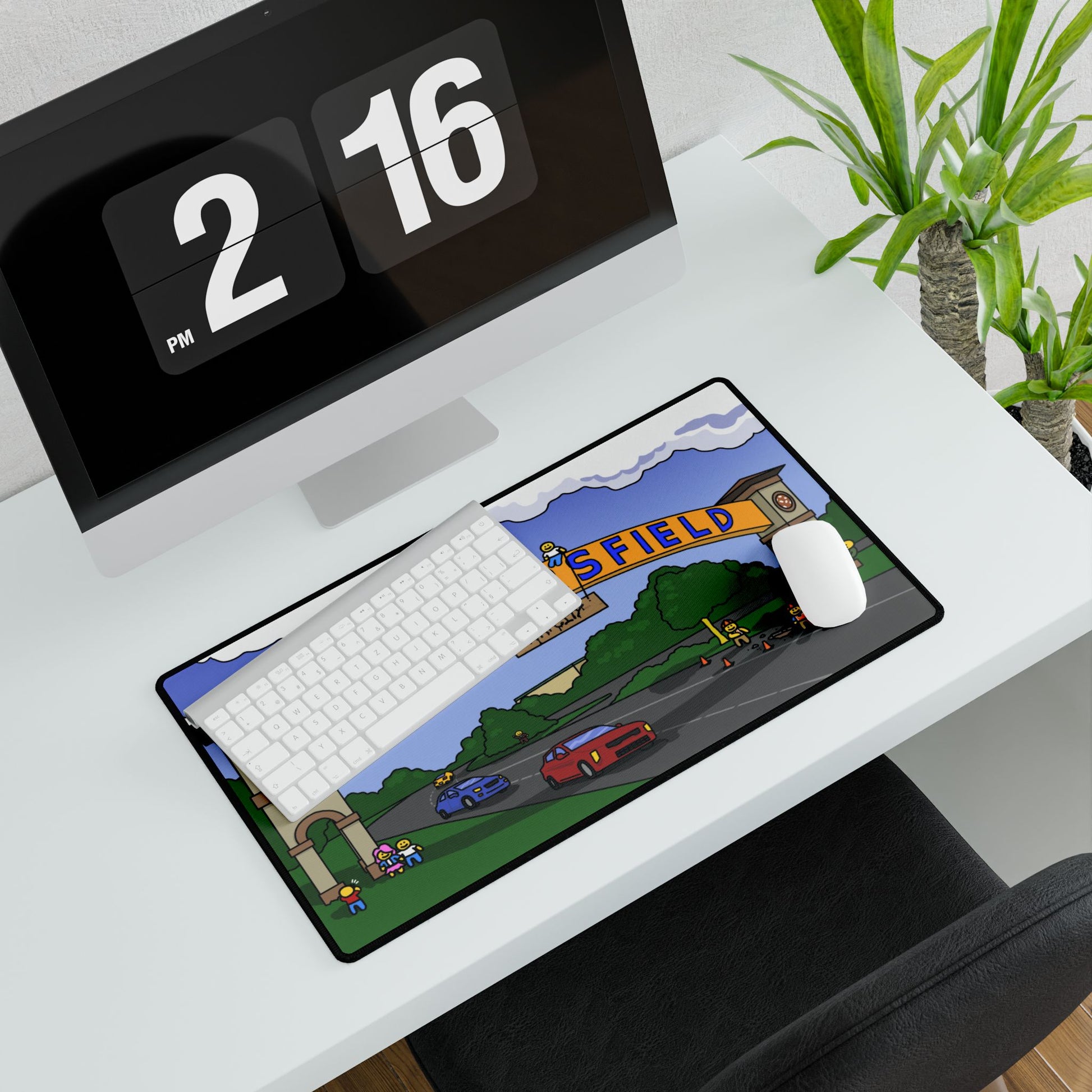 Medium Bakersfield mouse pad placed under keyboard and mouse; arch text partly visible with red car and green landscaping at edge of modern workspace.