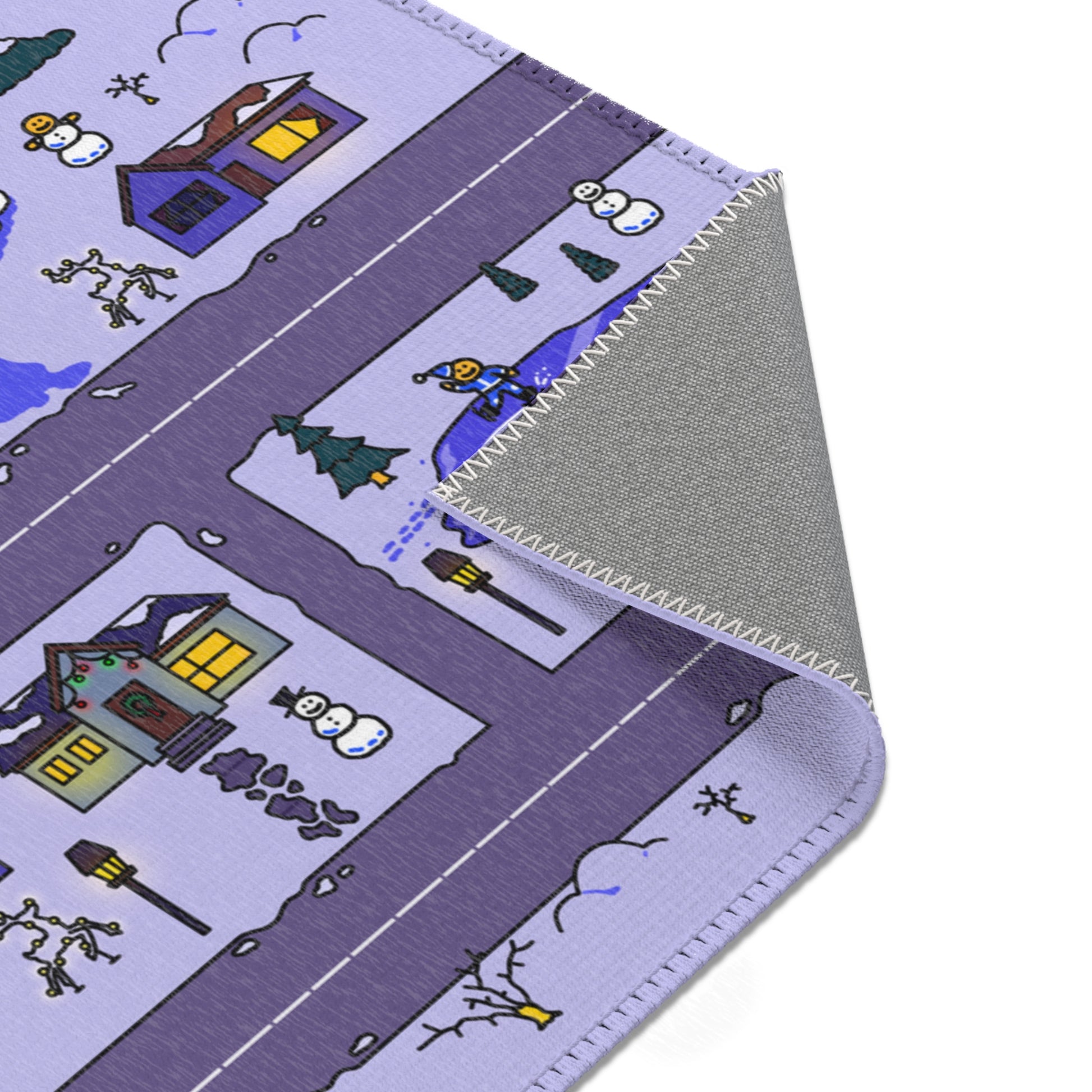 Close up of folded mat corner showing stitched edge, skating pond with elf, two mini snowmen, lit lamppost and snowy cottages on a road grid.