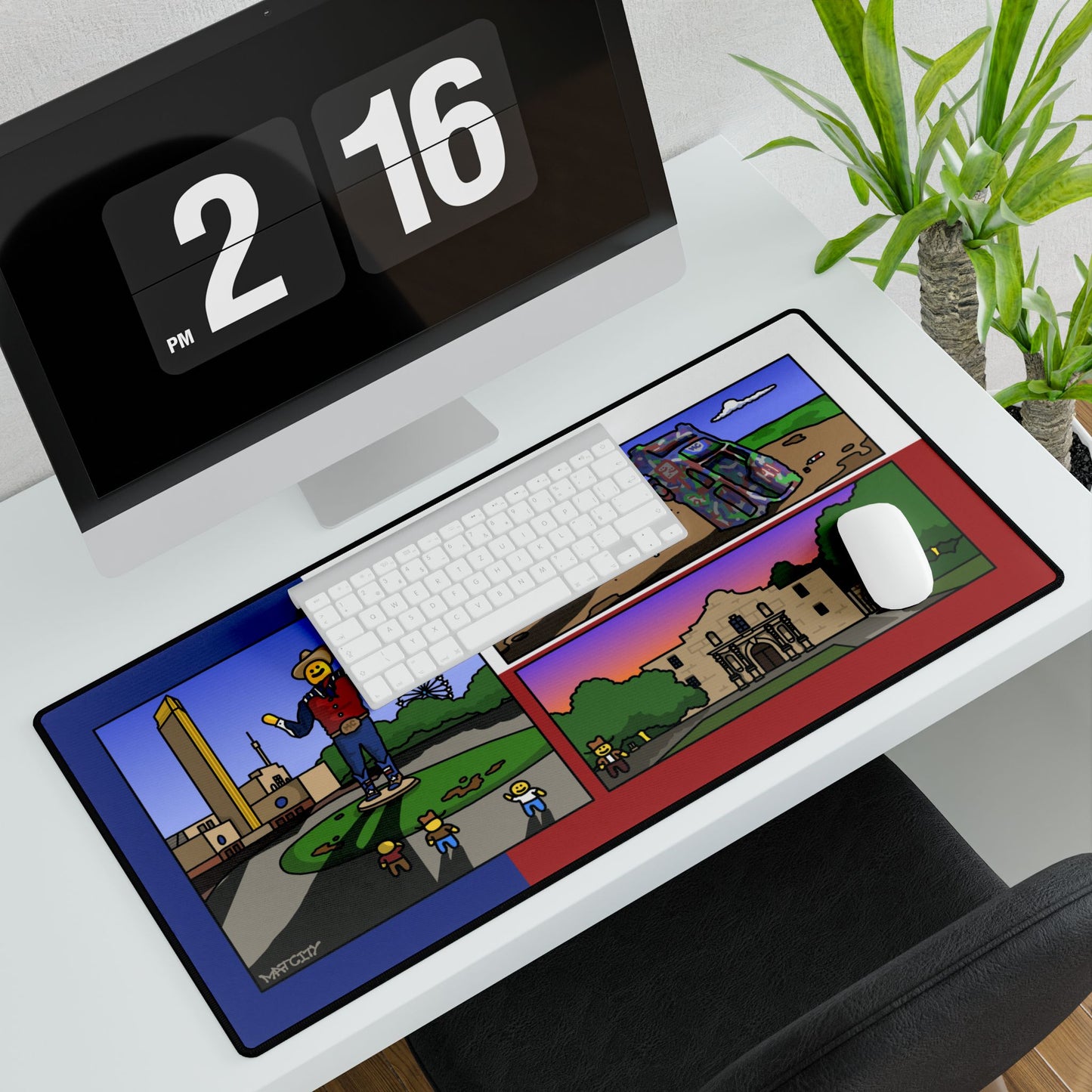 Overhead office view; keyboard and mouse sit on the large landmark desk pad beside a monitor and plant.